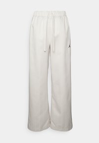 Pantalon blanc à jambes larges avec taille élastique et cordon, fines rayures verticales et petit logo Jumpman noir sur le côté gauche.