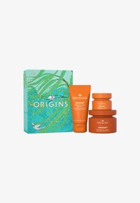 Origins GinZing hudpleiesett i en turkis boks med blomstermønster. Inneholder en oransje skrubb og to oransje krukker med krem.