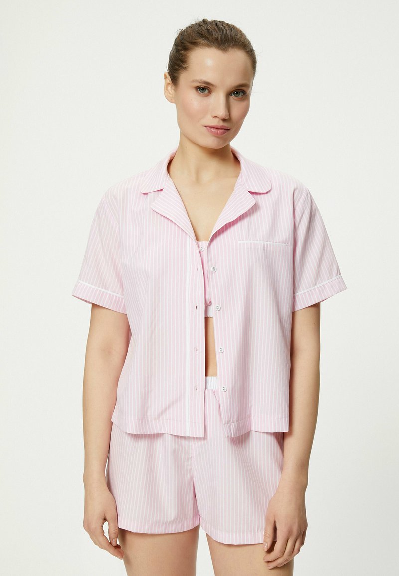 Conjunto de pijama de manga corta a rayas de color rosa claro, con una camiseta abotonada y pantalones cortos a juego, confeccionado en una tela suave y con un corte relajado.