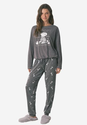 Grijs, lang mouwen pyjama top met Snoopy graphic; bijpassende grijze broek met witte Snoopy patronen en een taillekoord; gedragen met zachte pantoffels.