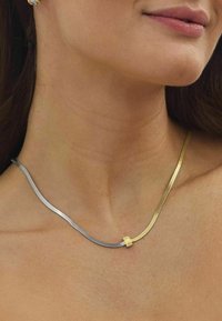 Collana bicolore con fili di metallo argento e oro, texture liscia, con un piccolo elemento decorativo in oro al centro.