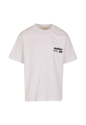 Tricou din bumbac alb cu guler rotund și mâneci scurte. Prezintă un mic logo imprimat negru în zona stângă a pieptului.
