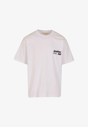 Weißes Baumwoll-T-Shirt mit Rundhalsausschnitt und kurzen Ärmeln. Mit einem kleinen schwarzen Drucklogo auf der linken Brustseite.