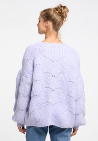Lavendelfarbener gestrickter Pullover mit strukturiertem Wellenmuster, oversized Design und lockerer Passform. Lange, weite Ärmel runden das Erscheinungsbild ab.