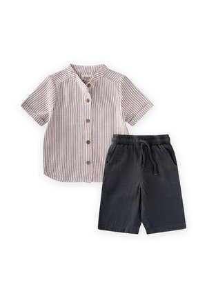 Chemise beige à manches courtes avec des rayures verticales et des boutons marron, associée à un short noir à taille élastique avec poches et cordon.