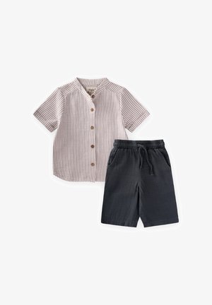 Chemise beige à manches courtes avec des rayures verticales et des boutons marron, associée à un short noir à taille élastique avec poches et cordon.