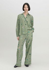 Olijfgroene langemouwen shirt en bijpassende broek met een bloemenpatroon. Glad materiaal met een relaxte pasvorm en wijde broekspijpen.