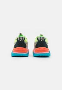 Vista posteriore di sneaker con tomaia in rete verde, accenti neri e suola rosa-arancio con dettagli blu e un logo.