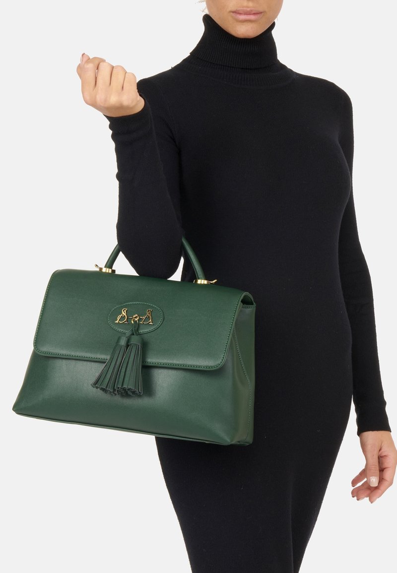 Zielona skórzana torebka z klapą, złotymi akcentami i frędzlami. Gładka faktura i uporządkowany, prostokątny kształt.