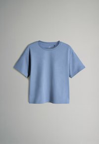 Camiseta de manga corta color azul claro, hecha de algodón suave. Presenta un cuello redondo y un corte relajado con detalles de costura mínimos.