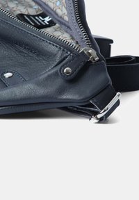 Borsa a tracolla in pelle blu scuro con accessori in argento, chiusura a zip e fodera interna a motivi. Cinghia regolabile visibile.