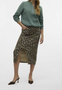 Vaaleanvihreä vetoketjullinen collegepaita, eläinprinttihame halkiolla ja ruskeat koristellut mules-kengät. Painotus tekstuureissa ja vastakohtaisissa kuoseissa.