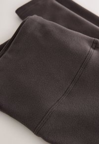 Dark gray fleece fabric folded, showing soft texture and visible seam stitching detail.