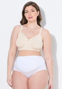 Beige bezdrátová podprsenka s krajkovým lemem a předním zapínáním, spárovaná s bílými vysokými hladkými kalhotkami, které mají jemnou, elastickou texturu.
