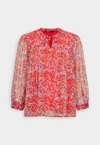 Blusa rossa floreale con maniche lunghe e trasparenti, dettaglio arricciato e scollo a chiave. Il motivo presenta fiori multicolori su uno sfondo vibrante.