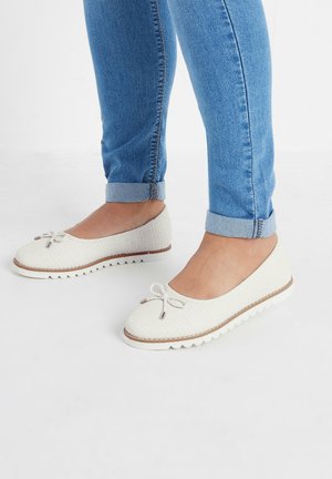 Bailarinas blancas tejidas con punta redondeada, lazo decorativo y parte superior texturizada. Presentan una suela de goma con un patrón ondulado.