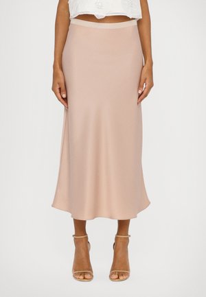 A long, blush satin skirt with a smooth texture and a slight flare. Features a fitted waistband and is paired with beige heeled sandals.