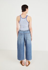 Prugasta majica na bretele z modrim obrubom, v kombinaciji s širokimi svetlo modrimi denim culottes, ki imajo dve zadnji žep in sproščen fit.