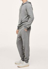 Szary zestaw z dzianinową bluzą z kapturem i spodniami dresowymi o luźnym kroju, z kieszenią kangurką i ściągaczami, w połączeniu z białymi adidasami.