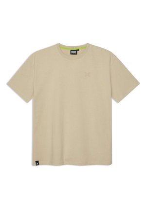 Beżowa bawełniana koszulka z krótkimi rękawami, okrągłym dekoltem i małym tłoczonym logo na piersi. Posiada neonowozieloną lamówkę wewnątrz kołnierza.