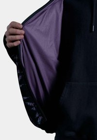 Sudadera con capucha de capa exterior negra y forro de malla morado, con un patrón floral decorativo en los puños. Textura suave, cierre con cremallera.