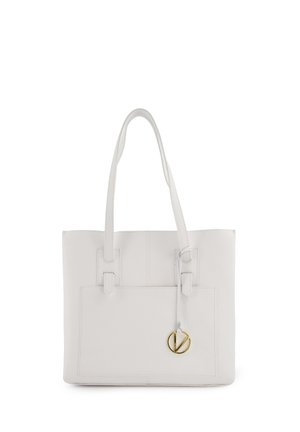 Witte leren tote bag met twee lange handvaten, een voorvak en een gouden cirkelvormige acccent. Glad textuur, gestructureerde vorm, minimale detailing.