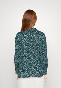 Long-sleeved shirt in lightweight fabric, featuring a blue and green abstract pattern on a black background. Classic collar, relaxed fit.