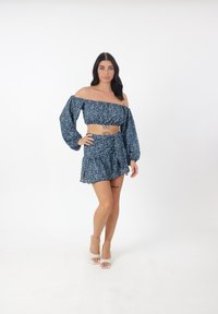 Top corto floral azul con mangas abullonadas combinado con una mini falda a juego. Tejido ligero, dobladillo volado y detalle atado en la cintura.