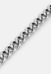 Bracelet en chaîne en métal argenté avec des maillons entrelacés, arborant une surface lisse et polie ainsi qu'un design arrondi.