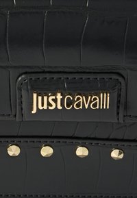 Černá umělá krokodýlí kůže s lesklým povrchem, s zlatým logem "just cavalli" a zlatými hroty podél švu.