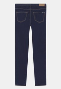 Vaqueros de mezclilla azul oscuro con una forma ajustada, que presentan dos bolsillos traseros, detalles sutiles de costuras y una etiqueta de cuero con la marca en la cintura.