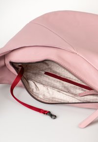 Borsa a mano in pelle rosa aperta, che mostra l'interno con fodera a fantasia, tasca con zip rossa e un cinturino da polso rosso con gancio in metallo.