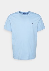 Jasnoniebieska bawełniana koszulka z krótkim rękawem, okrągłym dekoltem i małym logo na piersi. Miękka faktura i casualowy design.