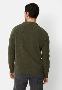 Mørkegrøn tekstureret sweater med rund halsudskæring og ribstrikkede manchetter. Bagfra ses et tætsiddende design med en lige kant.
