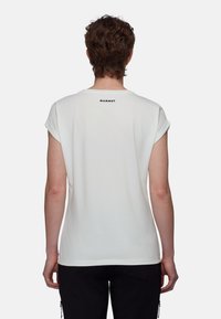 Biała koszulka z krótkim rękawem z podwiniętymi mankietami, z małym czarnym logo "MAMMUT" na górnej części pleców. Gładka faktura tkaniny.