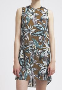 Hedvábné bezramínkové šaty s květinovým vzorem na hnědém pozadí, se velkými zelenými a bílými listy a bílými květy. Hladká tkanina s uvolněným střihem.