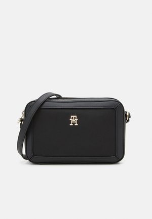Borsa a tracolla sintetica nera con forma rettangolare, accentuata da un logo dorato, chiusura con zip e tracolla regolabile. Texture liscia con bordi cuciti.