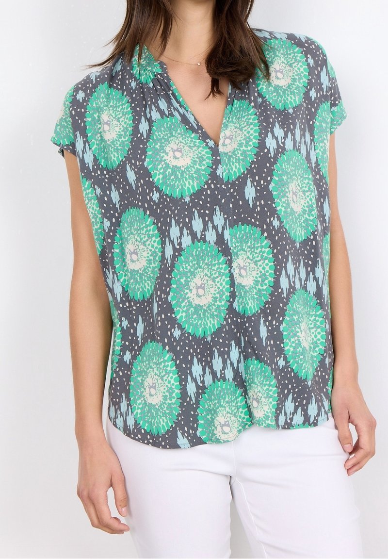 Blusa a maniche corte in tessuto leggero, con sfondo grigio e motivi floreali verdi e accenti blu. Design a V.