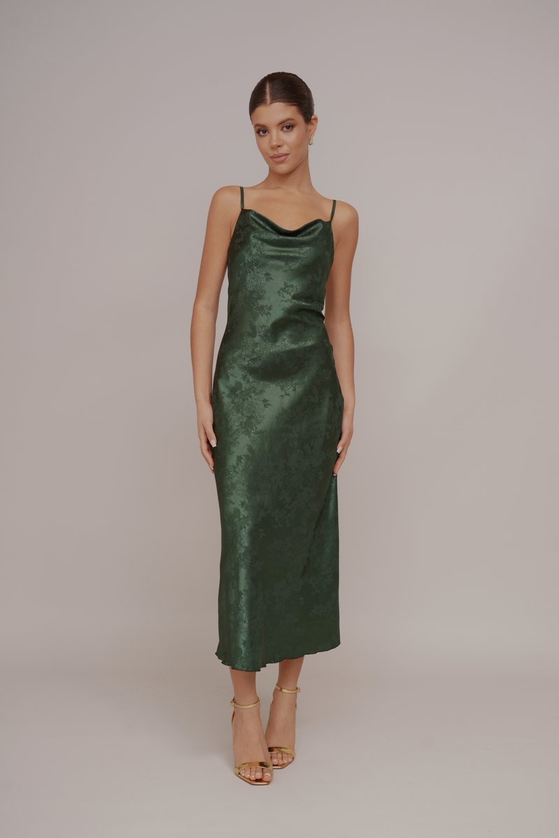 Gröna satinmidiklänning med cowl-halsringning, tunna remmar och blommönster. Kombinerad med guld ankle strap sandaler. Slät, elegant struktur.