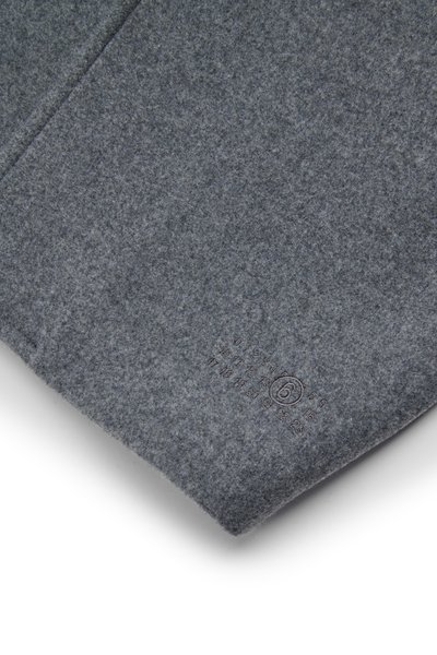 Szary materiał filcowy o miękkiej teksturze, z subtelnym połyskiem. W dolnym rogu znajduje się wypukły metka z informacjami o rozmiarze.