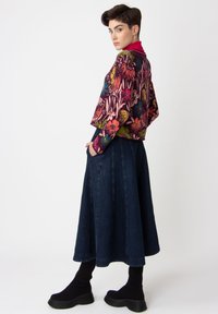 Blommönstrad kort jacka i mörka färger, ihop med en lång jeanskirt och kraftiga svarta platåstövlar. Slät textur, avslappnad passform.