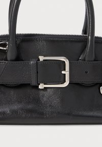 Borsa a mano in pelle nera con finitura lucida, doppi manici superiori e una fibbia in metallo argentato come dettaglio su una cinghia attraversata frontalmente.
