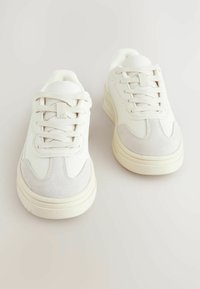 Witte sneakers met een gladleren en suède bovenwerk, ronde neus, vetersluiting en een dikke rubberen zool, met subtiele stiksels.