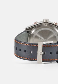 Zegarek chronograf z granatowym skórzanym paskiem z pomarańczowym haftem, polerowaną stalową kopertą i bezpiecznym srebrnym zapięciem.