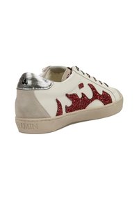 Zapatilla blanca tipo baja con diseño de llamas de glitter rojo en el costado, pestaña metálica plateada en el talón, parte trasera de ante beige y suela beige con la inscripción "GAMIN".