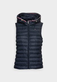 Granatowa pikowana kamizelka bez rękawów typu puffer z kapturem, zapinana na zamek z przodu i małym logo na piersi na jednolitym tle.