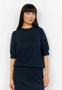 Top blu navy a maniche corte con scollatura rotonda e maniche a palloncino. Tessuto morbido con una texture liscia; design con vestibilità rilassata.