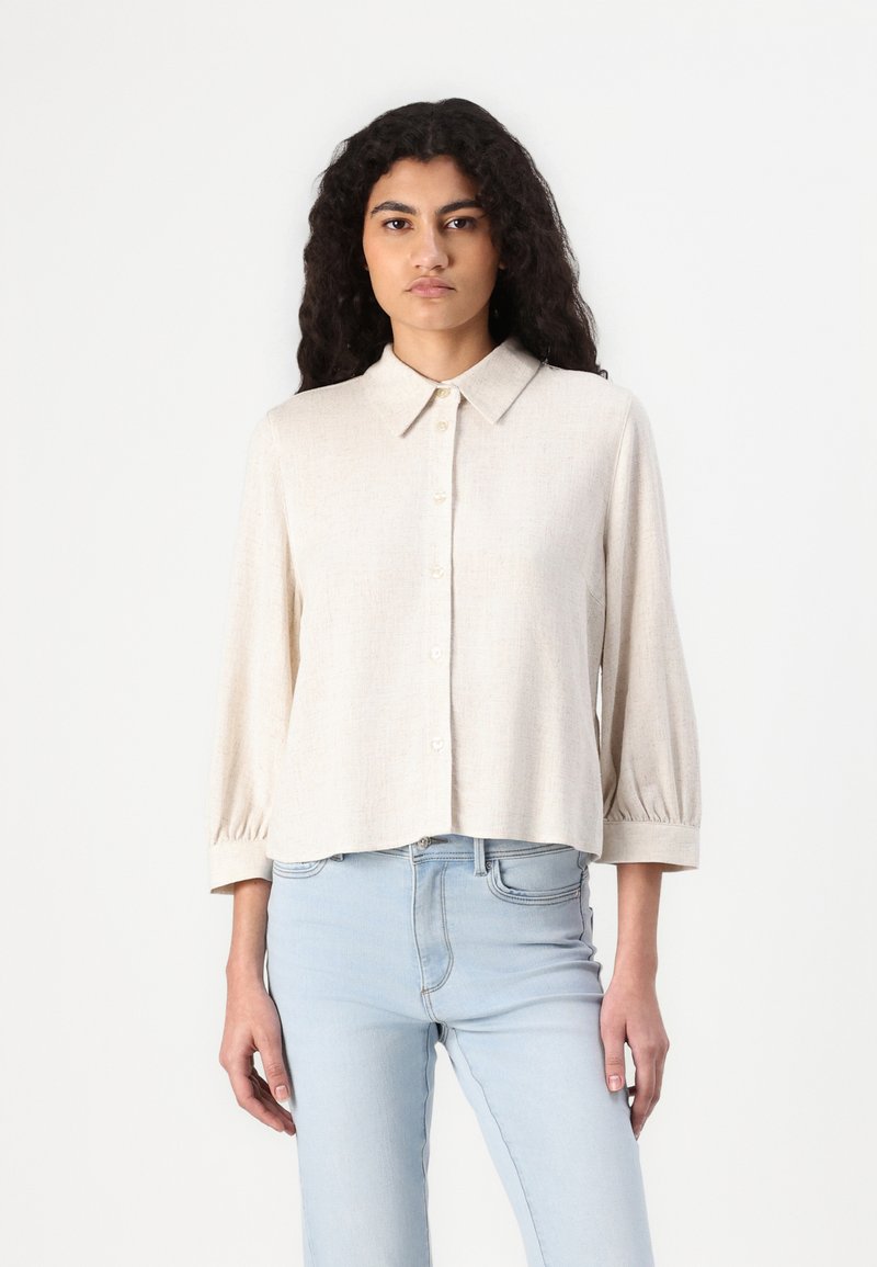 Lys beige skjorte med krage, trekvart lange ermer og avslappet passform, laget av et strukturert stoff. Glatt finish.