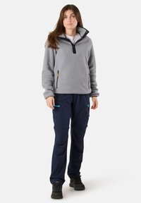 Gray fleece pullover with high collar and half zipper, paired with navy cargo pants featuring multiple pockets and bright zipper accents.