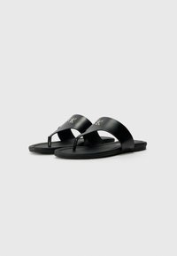 Sorte lærflip-flops med et minimalistisk design, som har en flad sål, tætsiddende strop og logo-detail på den øverste rem.